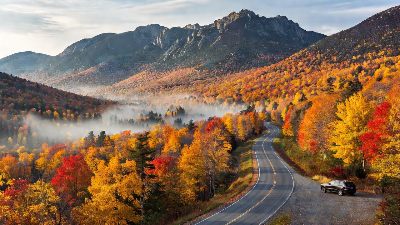 A scenic overlook along a winding mountain highway through the White Mountains during peak fall foliage